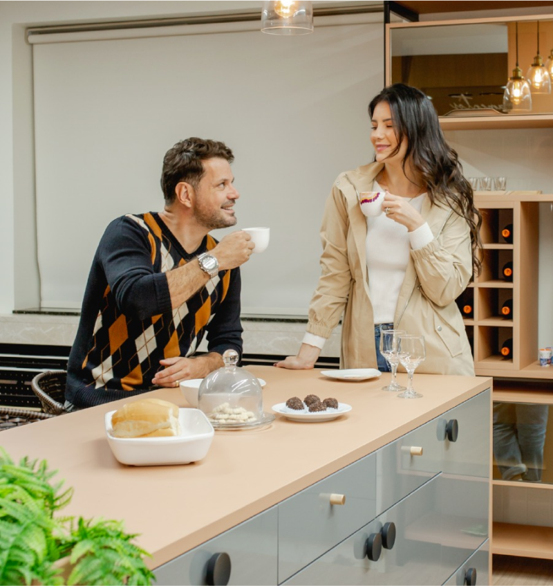 Um homem e uma mulher tomando café em uma cozinha planejada